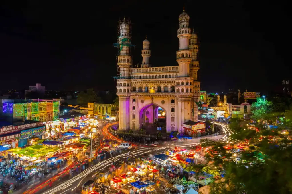 Illuminated Charminar monument with bustling street and light trails