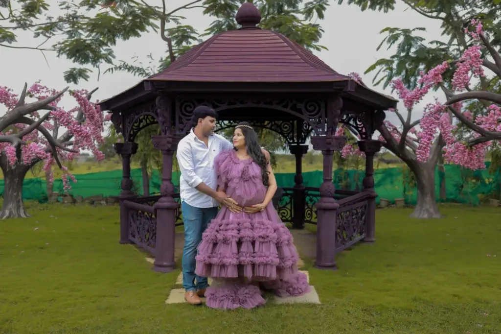 Expectant mother in purple dress framed by circular floral arch