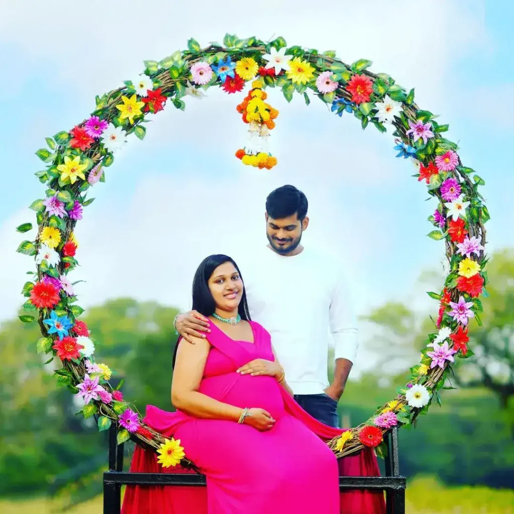 Couple framed by circular floral arch – pregnancy photoshoot in Hyderabad park
