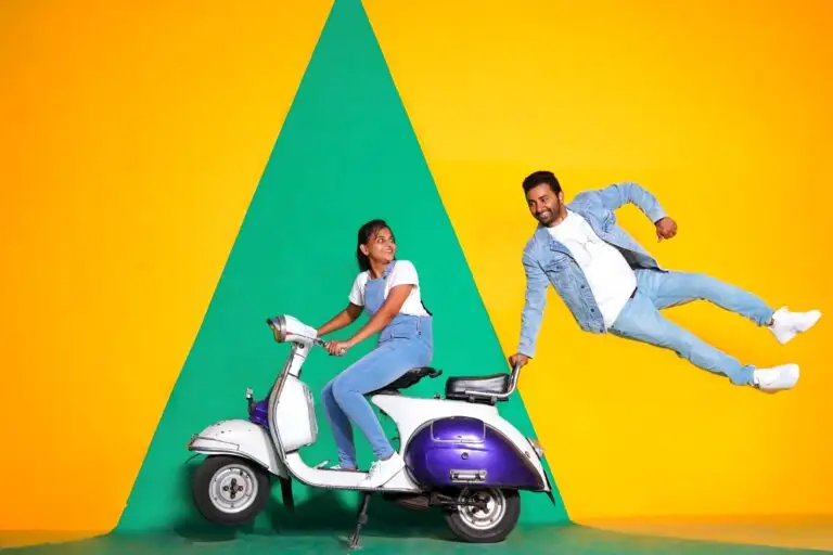 Woman riding pastel scooter with partner jumping against yellow-green backdrop