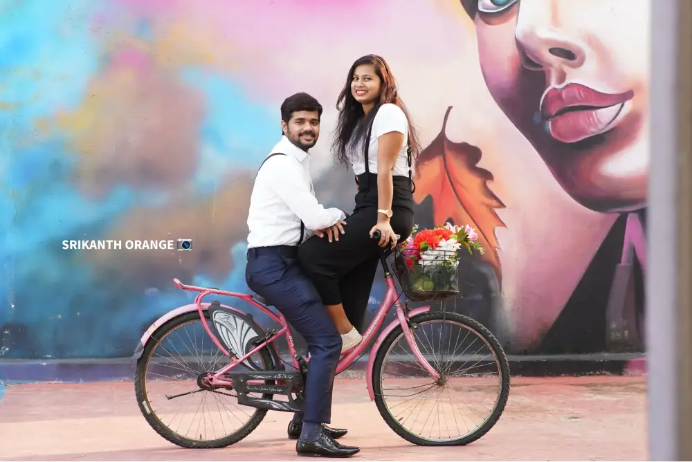 Couple on pink bicycle in front of stylized mural – pre wedding shoot Hyderabad